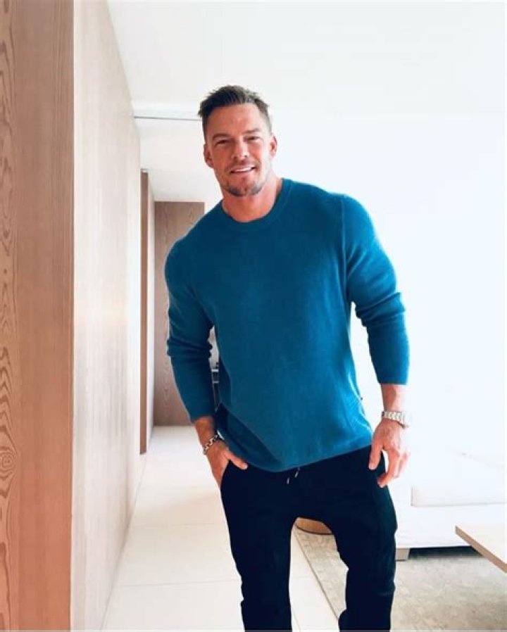 Alan wearing white t-shirt with black pants.