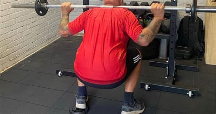 James Charles squatting on the gym.