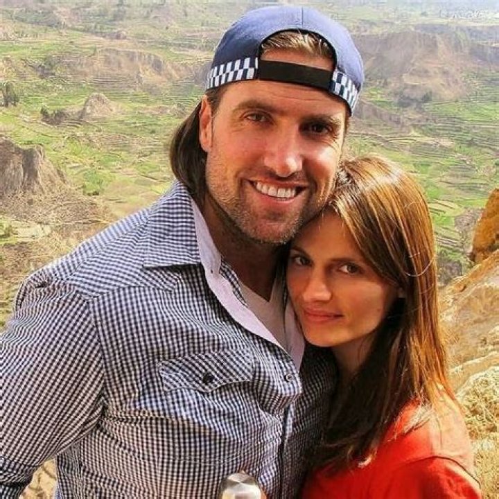 Kris Brkljac smiling with his wife Stana Katic in a cap and blue lined shirt.
