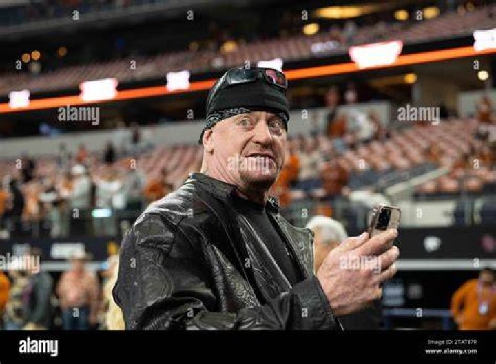 Mark William Calaway in a grey skull caps and navy blue t-shirt with his wife Michelle McCool in a black thin-laced top.