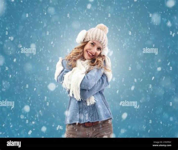 She is smiling at the camera while holding a coffee cup in one hand and her phone in another.