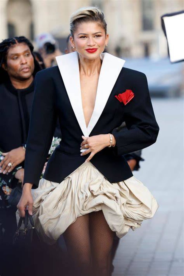 Zendaya in a black jacket with her father in a dark chocolaty t-shirt and her mother in a white dress.